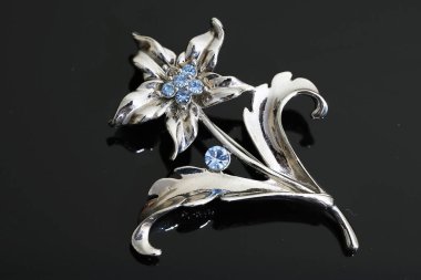 Gümüş çiçekli ve mücevherli bir broş.