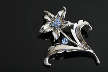 Gümüş çiçekli ve mücevherli bir broş.
