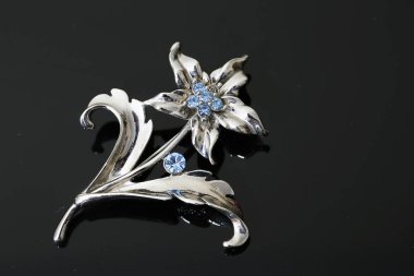Gümüş çiçekli ve mücevherli bir broş.