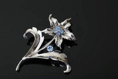 Gümüş çiçekli ve mücevherli bir broş.