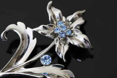 Gümüş çiçekli ve mücevherli bir broş.