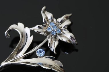 Gümüş çiçekli ve mücevherli bir broş.