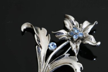 Gümüş çiçekli ve mücevherli bir broş.