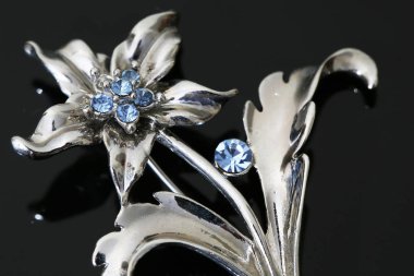 Gümüş çiçekli ve mücevherli bir broş.