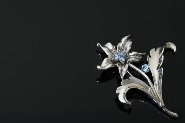 Gümüş çiçekli ve mücevherli bir broş.