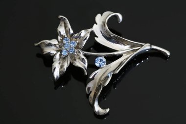 Gümüş çiçekli ve mücevherli bir broş.
