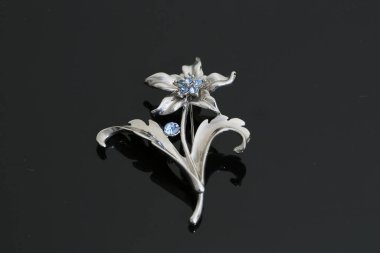 Gümüş çiçekli ve mücevherli bir broş.