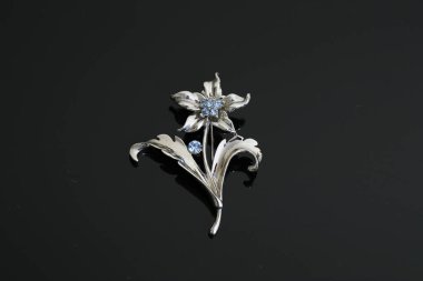 Gümüş çiçekli ve mücevherli bir broş.