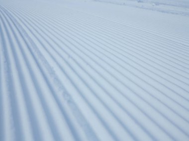 Kar kadifesi kayak yamacına yakın. Kar üzerinde kar temizleyicisi izi olan kayak ve snowboard pisti hazırlandı