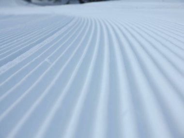 Kar kadifesi kayak yamacına yakın. Kar üzerinde kar temizleyicisi izi olan kayak ve snowboard pisti hazırlandı