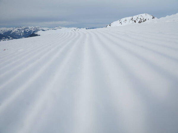 Snow velvet close up on ski slope. Prepared ski and snowboard track with trace of snow groomer on snow