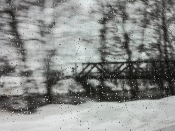 Raindrops on window with the picturesque winter landscape. — Stock Photo, Image