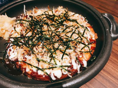 Okonomiyaki - geleneksel Japon boşaltmak pizzayla tabak sıcak. Koyu tonu.