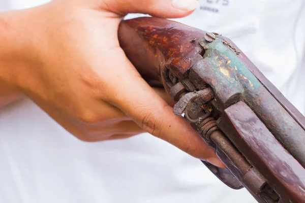 Horizontal photo of closeup hand holding old gun, selective focus on the gun. — Stock Photo, Image