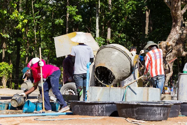 LAMPANG, THAILANDIA - 5 NOVEMBRE: adolescenti thailandesi non identificati nel campo di lavoro mescolando cemento e macchina miscelatrice il 5 novembre 2016 a Lampang, Thailandia . — Foto Stock