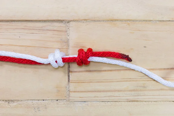 Fisherman's knot made with red rope on wooden background. — Stock Photo, Image