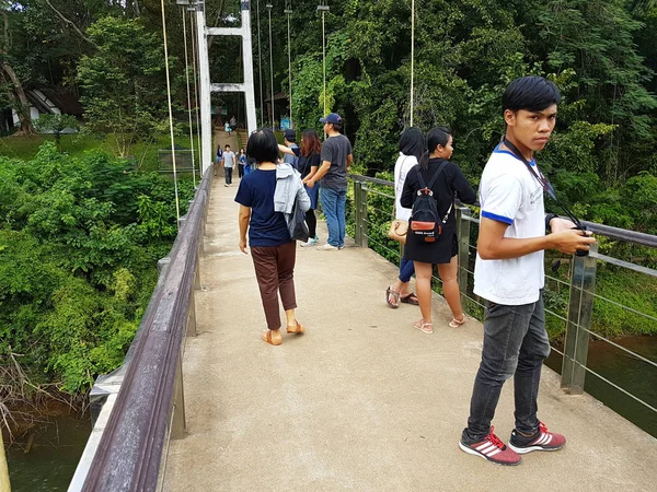 KANCHANABURI, TAILANDIA - 26 DE NOVIEMBRE: turistas asiáticos no identificados caminando sobre el puente colgante para peatones que cruzan el río Kwai en el Parque Nacional Sai Yok el 26 de noviembre de 2016 en Kanchanaburi, Tailandia —  Fotos de Stock