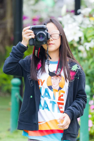 CHIANG RAI, TAILANDIA - 12 DE FEBRERO: Pequeña asiática no identificada con gafas y vendaje para los ojos usando la cámara réflex digital el 12 de febrero de 2017 en Chiang rai, Tailandia . — Foto de Stock