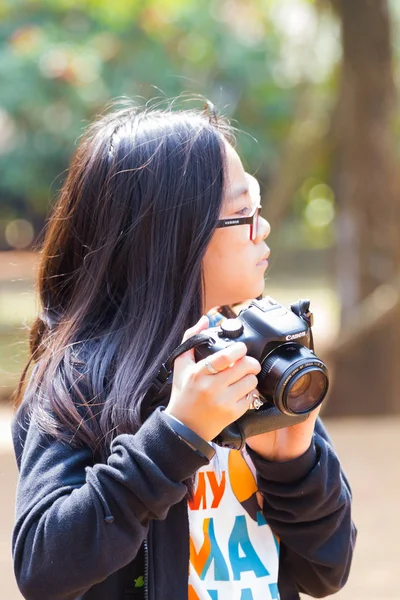 CHIANG RAI, THAILAND - FEVEREIRO 12: Menina asiática não identificada com óculos e bandagem ocular usando câmera DSLR em fevereiro 12, 2017 em Chiang rai, Tailândia . — Fotografia de Stock