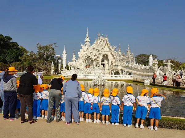 Chiang Rai, Thajsko - březen 1: skupina neznámých asijských studentů s žlutá čepice na exkurzi v chrámu Wat Rong Khun děje 1. března 2017 v Chiang rai, Thajsko — Stock fotografie