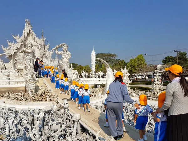 Chiang Rai, Thailand - 1 maart: groep van niet-geïdentificeerde Aziatische studenten met gele caps gaande is een excursie op Wat Rong Khun Tempel op 1 maart 2017 in Chiang rai, Thailand — Stockfoto