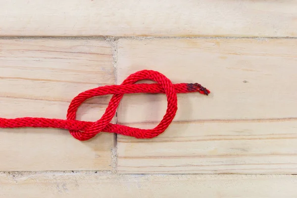 Figure-huit noeud en corde rouge sur fond en bois — Photo