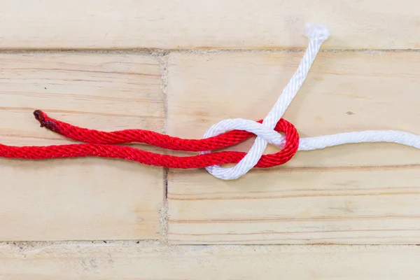 Bogen-Biegeknoten aus rotem Seil auf Holzgrund. — Stockfoto