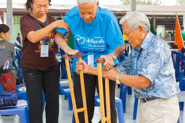 CHIANG RAI, TAILANDIA - 20 DE FEBRERO: pareja no identificada ayudando a un anciano asiático con lepra el 20 de febrero de 2016 en Chiang rai, Tailandia . — Foto de Stock