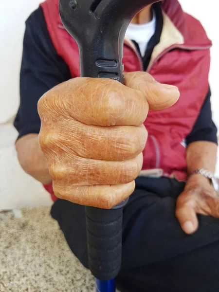 Primer plano mano de viejo asiático macho con un reloj sosteniendo un bastón — Foto de Stock