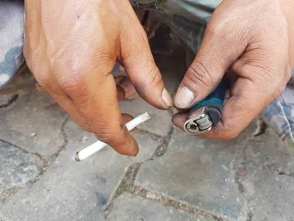 Closeup asian man's hand holding burning traditional cigarette with lighter in hand — Stock Photo, Image