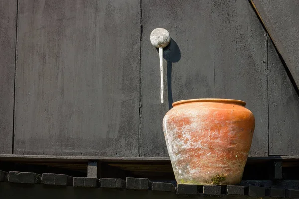 Orangefarbener Wasserjaron auf dem schwarzen Hintergrund einer alten Holzwand, mit Kopierraum rechts — Stockfoto