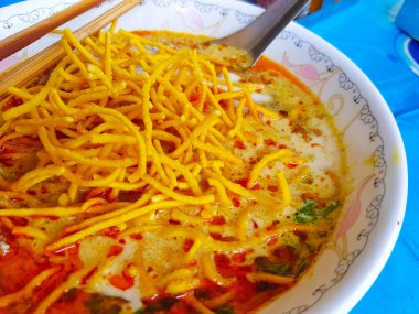 Khao Soi, Kuzey Tayland tarzı Curried şehriye çorbası yemek çubukları ve mavi masa kaşık ile