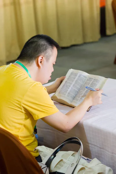 Phetchaburi, thailand - 7. April 2017: unbekannter Junge mit Down-Syndrom liest Bibel am Strand am 7. April 2017 in phetchaburi, thailand. — Stockfoto