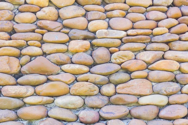 River pebbles round stone wall background — Stock Photo, Image