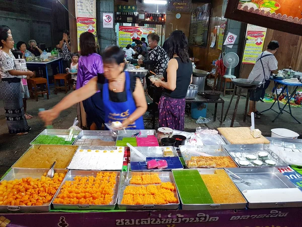 KAMPHAENG PHET, THAILANDIA - 6 MAGGIO: donna asiatica non identificata con abbigliamento tradizionale tailandese che vende vari dessert nel mercato di strada di Nakhon Chum il 6 maggio 2017 a Kamphaeng Phet, Thailandia . — Foto Stock