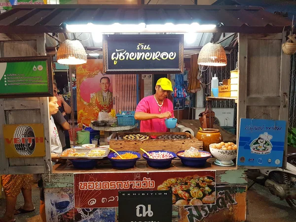 KAMPHAENG PHET, THAILANDIA - 6 MAGGIO: uomo asiatico non identificato con abbigliamento tradizionale tailandese che vende omelette di ostriche nel mercato di strada di Nakhon Chum il 6 maggio 2017 a Kamphaeng Phet, Thailandia . — Foto Stock