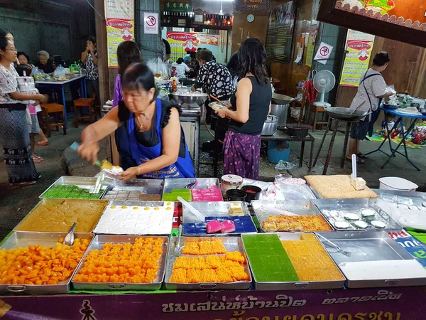 KAMPHAENG PHET, TAILANDIA - 6 DE MAYO: mujer asiática no identificada con ropa tradicional tailandesa que vende postres variuos en el mercado callejero por la noche el 6 de mayo de 2017 en Kamphaeng Phet, Tailandia . —  Fotos de Stock