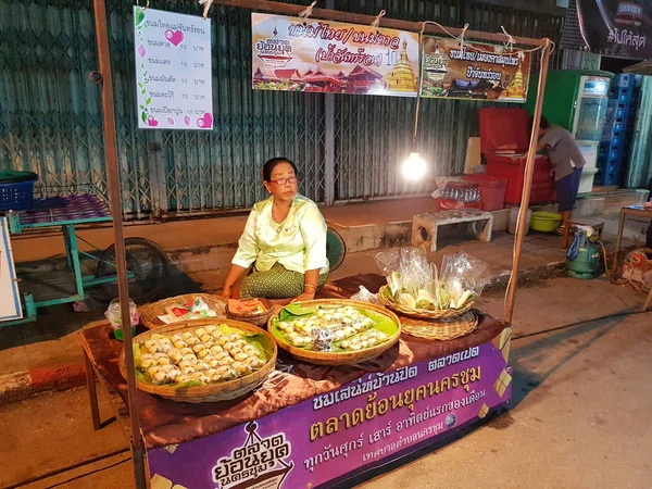 KAMPHAENG PHET, THAILAND - MAJ 6: uidentificeret asiatisk kvinde med thailandsk traditionelt tøj, der sælger thailandsk dessert i Nakhon Chum gademarked den 6. maj 2017 i Kamphaeng Phet, Thailand . - Stock-foto