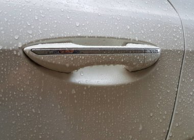 Yağmur damlaları ile beyaz bir otomobilin ön kapı kolu.