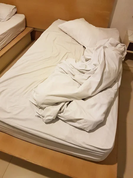 Незроблене безладне ліжко зі зморщеними листами і ковдрами після сексу — стокове фото