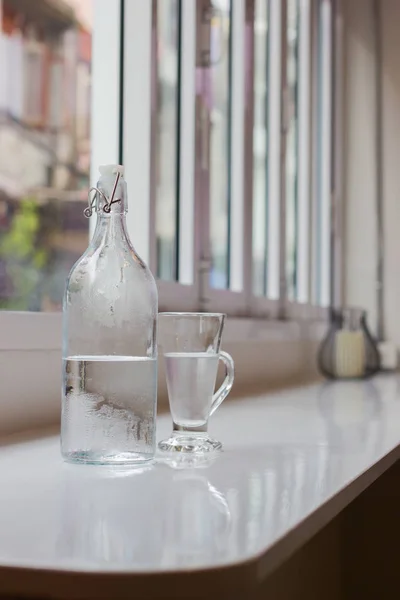 Glass of water with a bottle on table. Shallow depth of field. vertical photo — Stock Photo, Image
