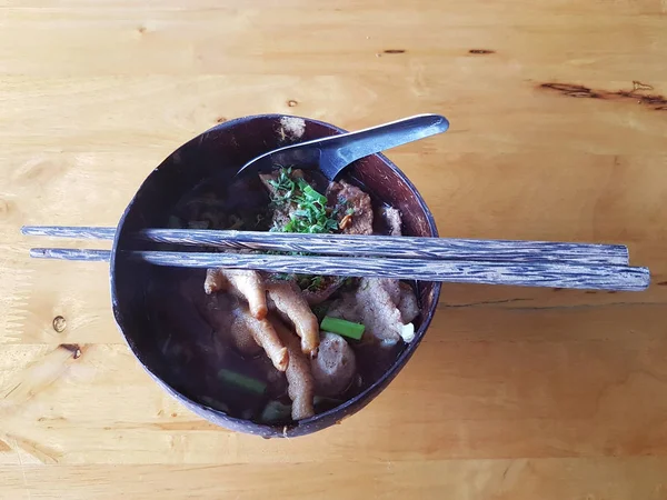 Macarrão com pernas de frango em tigela de casca de coco e pauzinhos e colheres — Fotografia de Stock