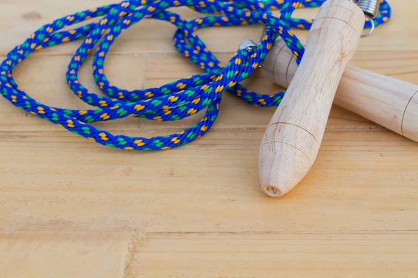 Cuerda de salto azul primer plano con mango de madera en bakcgroun de madera —  Fotos de Stock