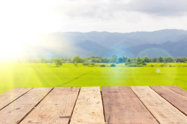 Perspective wooden board empty table in front of blurred background of rice field landscape with lens flare, can be used for display or montage your products. Mock up for displaying product. — Stock Photo, Image