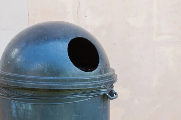 Primer plano cubo de basura negro con un agujero en el fondo pálido de la pared, espacio de copia a la izquierda —  Fotos de Stock