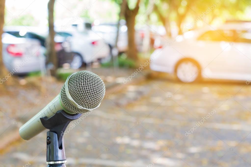 microphone on a stand with blurred vehicles in car park background. Copyspace.