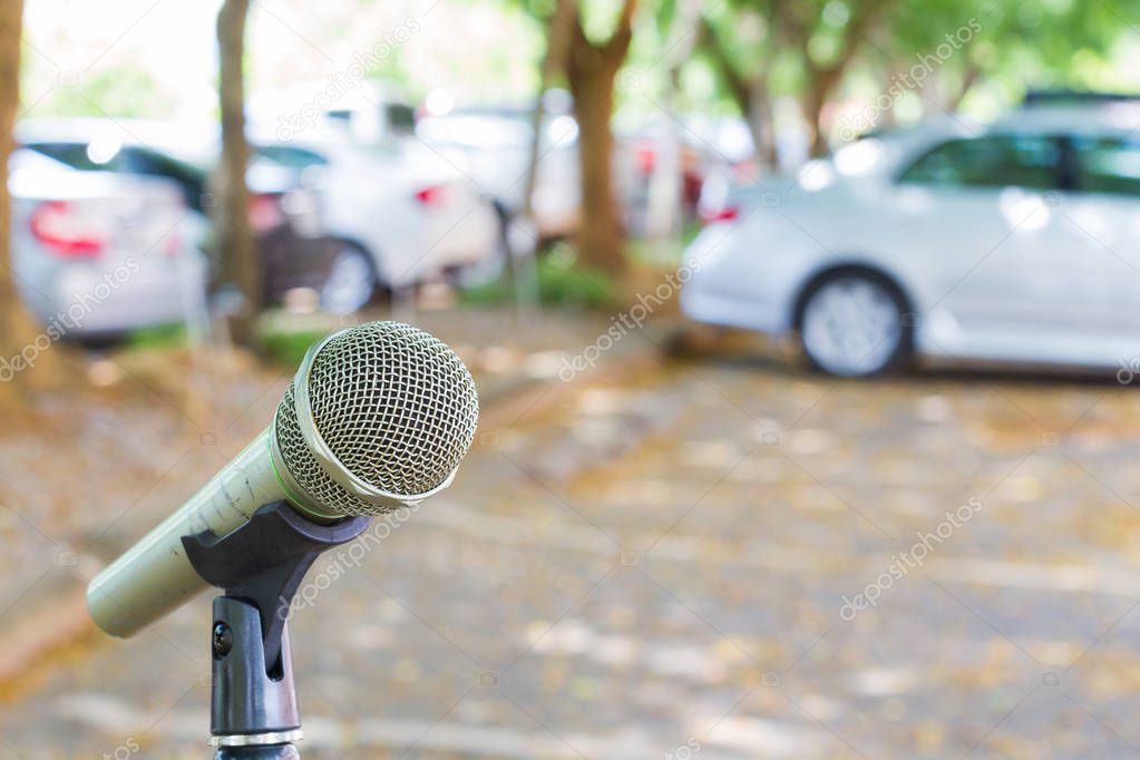 microphone on a stand with blurred vehicles in car park background. Copyspace.