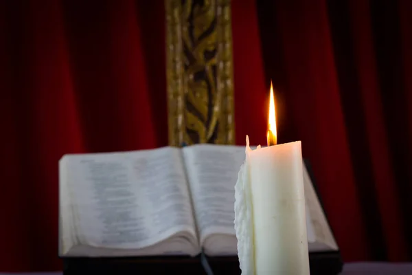 Bijbel met kaarsen op de achtergrond. Weinig licht scène. — Stockfoto