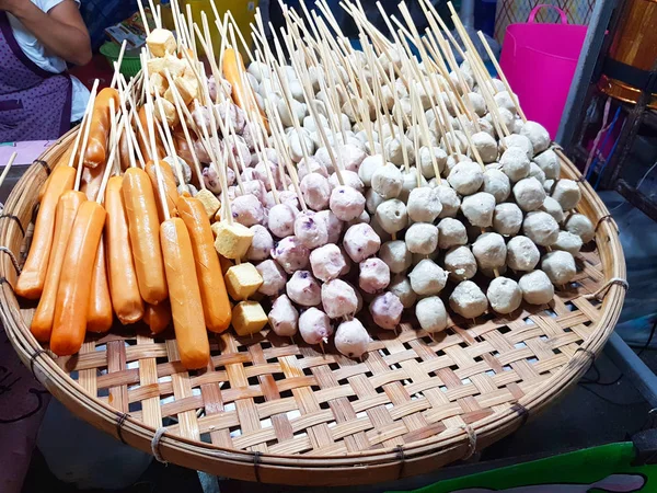 Polpette di carne e salsicce fumanti su vassoio di legno al mercato ambulante tailandese — Foto Stock