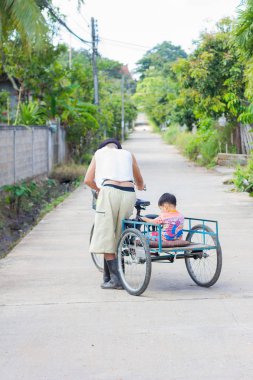Chiang Rai, Tayland - 5 Kasım: üç tekerlekli bisiklet Chiang rai, Tayland 5 Kasım 2017 ile birlikte torunu arka yolda iterek tanımlanamayan Engelli Asyalı yaşlı adam